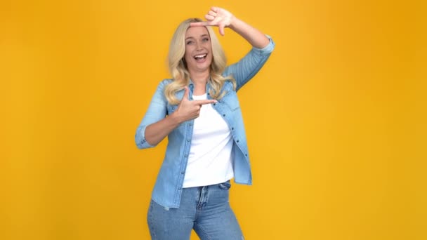 Очаровательная харизматичная блондинка показывает рамку жеста представьте себе сделать фото — стоковое видео