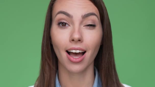 Позитивный женский портрет зубастая улыбка подмигивает изолированный зеленый цвет фона — стоковое видео