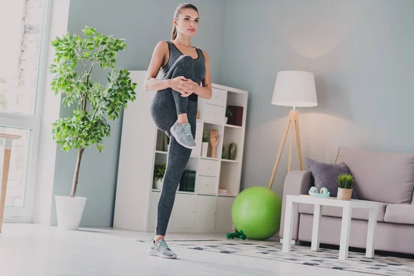 Foto de dulce adorable chica vestida traje de deporte silla trasera practicando entrenamiento dinámico sonriendo en el interior de la casa casa —  Fotos de Stock