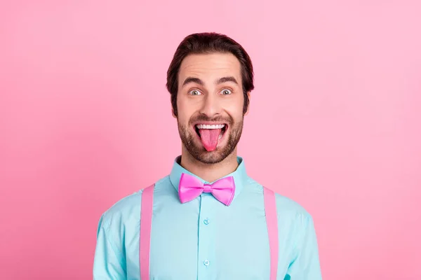 Photo drôle dupe jeune homme porter tenue turquoise souriant montrant la langue isolée fond de couleur rose — Photo