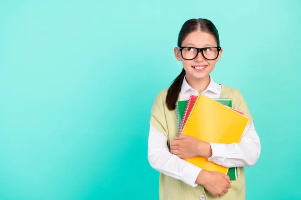 Foto von neugierig durchdachte Schulmädchen halten Haufen Copybook suchen leeren Raum tragen grüne Top isoliert Krickente Farbe Hintergrund — Stockfoto
