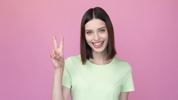 Optimistische dame maken v teken groet vriend geïsoleerde roze kleur achtergrond — Stockvideo