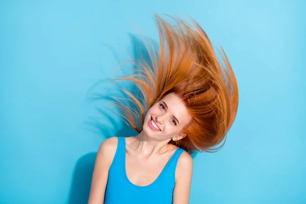 Çekici, neşeli bir kızın portresi parlak mavi arka planda izole edilmiş parlak saçlar atıyor. — Stok fotoğraf