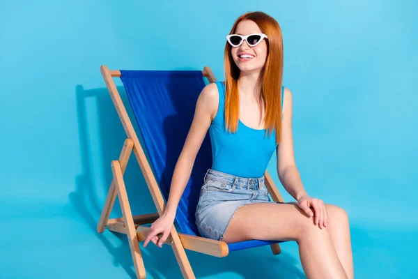 Foto von süßen charmante junge Dame gekleidet Body Top lächelnd mit Ruhe Chaiselongue isoliert blaue Farbe Hintergrund — Stockfoto