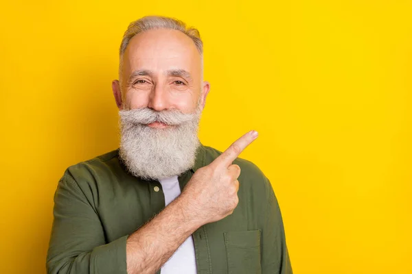 Photo portrait of elder man showing blank space with finger advising isolated vivid yellow color background — Stock Photo, Image