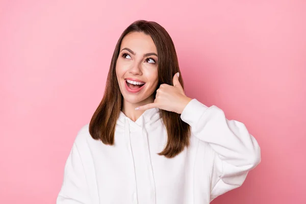 Foto di impressionato carino giovane signora indossare felpa bianca sorridente mostrando gesto del telefono cercando spazio vuoto isolato colore rosa sfondo — Foto Stock