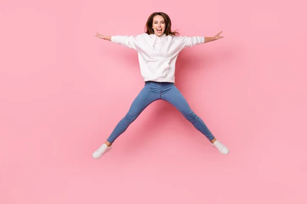 Foto de tamaño completo de lindo millennial señora morena salto usar pantalones vaqueros con capucha blanca aislados en el fondo de color rosa —  Fotos de Stock