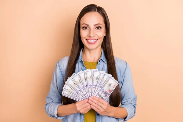 Foto de alegre jovem senhora segurar fã de dinheiro de dólares loteria vencedor jackpot isolado no fundo cor bege — Fotografia de Stock