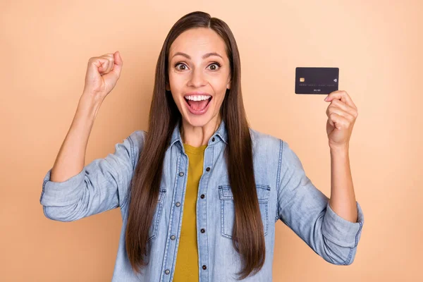 Foto av glada skrikande kvinna höja nävarna i seger prestation vinna pengar hålla kreditkort isolerad på beige färg bakgrund — Stockfoto