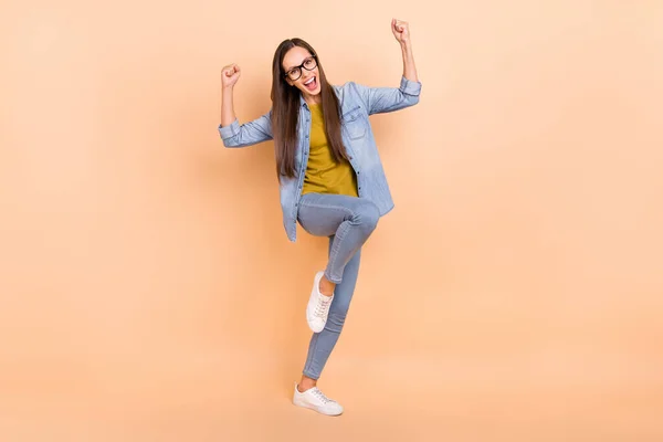 Foto de tamaño completo de la mujer positiva levantar los puños en triunfo victoria usar jeans camisa casual aislado sobre fondo de color beige —  Fotos de Stock