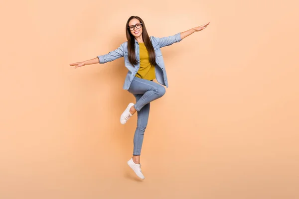 Foto in voller Größe von positiven schönen funky Dame springen Spreizung Hände Ebene posieren isoliert auf beige Farbhintergrund — Stockfoto