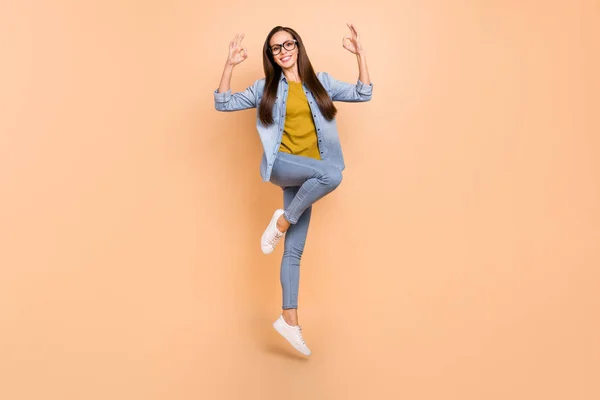 Foto in voller Größe von lächelnden reifen Dame springen zeigt okay Zeichen tragen Brille isoliert auf beige Farbhintergrund — Stockfoto