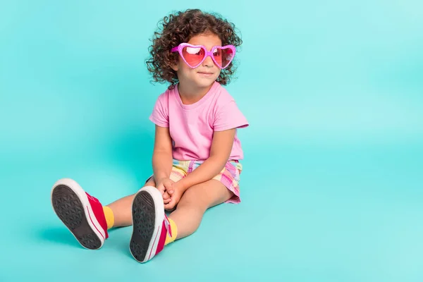 Retrato de menina alegre atraente vestindo grandes especificações rosa sentado descansando isolado sobre fundo de cor azul-turquesa brilhante teal — Fotografia de Stock