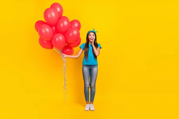 Full tělo fotografie mladé hezké dívky vzrušené neočekávané držet mnoho inflačních balónky izolované přes žlutou barvu pozadí — Stock fotografie