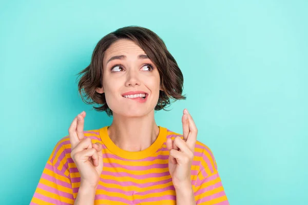 Φωτογραφία από χαριτωμένο αβέβαιο νεαρή γυναίκα ντυμένος ριγέ t-shirt δάχτυλα σταυρωμένα χείλια δάγκωμα αναζητούν κενό χώρο απομονωμένο φόντο teal χρώμα — Φωτογραφία Αρχείου