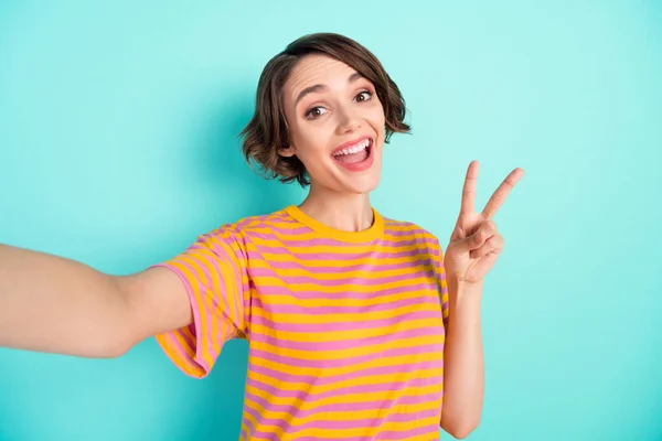 Foto van glanzende schattige jonge vrouw gekleed gestreepte t-shirt spijkeren selfie tonen v-teken geïsoleerde teal kleur achtergrond — Stockfoto