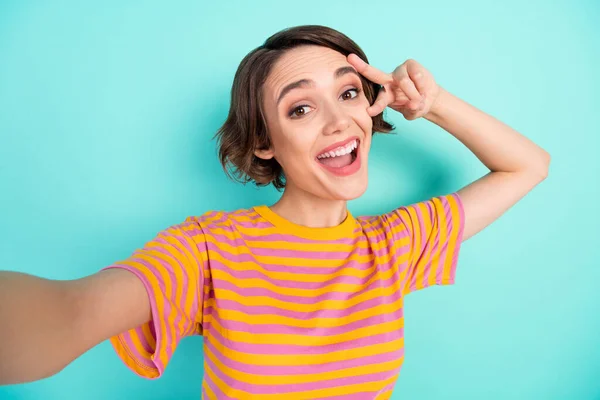 Foto de animado engraçado jovem mulher vestida listrado t-shirt tacking selfie v-sign capa olho isolado cor teal fundo — Fotografia de Stock