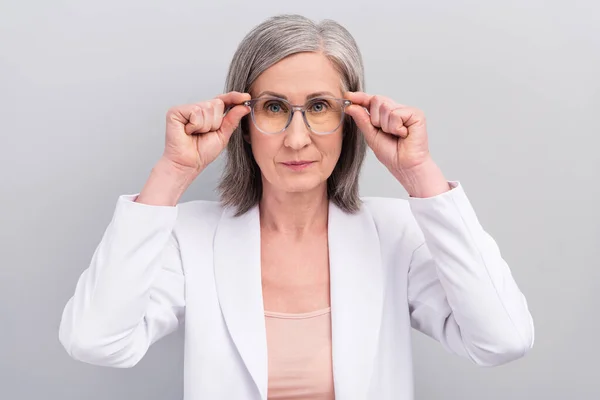 Foto de rigoroso penteado branco ancião senhora desgaste óculos casaco isolado no fundo de cor cinza — Fotografia de Stock