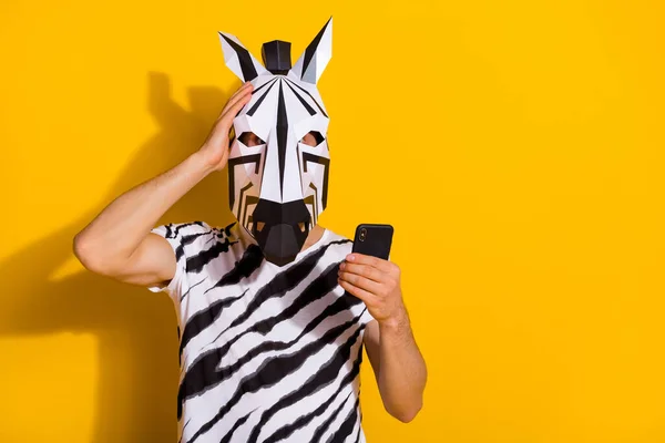 Foto von überrascht Kerl in Zebra-Maske lesen Medien Nachrichten Smartphone Touch Hand Kopf isoliert über helle gelbe Farbe Hintergrund — Stockfoto