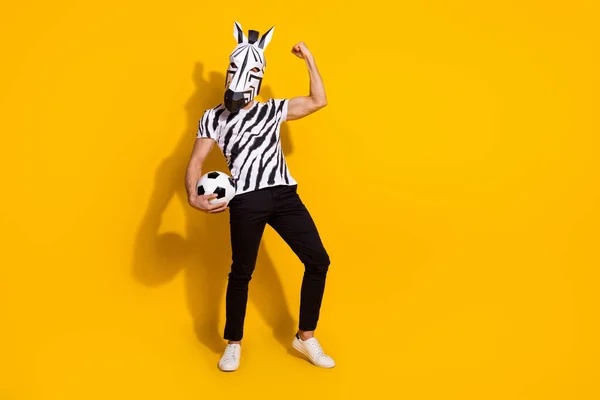 Foto in voller Größe von seltsamen Freak Kerl in Zebra-Maske halten Ball Faust nach oben Sieg World League Cup isoliert über gelben Farbhintergrund — Stockfoto