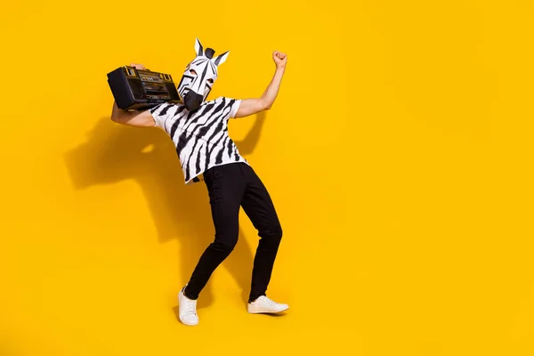 Foto de hombre afortunado divertido desgaste cebra impresión camiseta máscara escuchar boombox baile levantamiento puño vacío espacio aislado color amarillo fondo — Foto de Stock