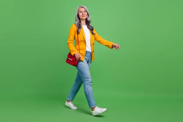 Ganzkörperprofil Seite Foto der schönen Rentnerin zu Fuß Urlaub Freizeitkleidung isoliert über grüne Farbe Hintergrund — Stockfoto