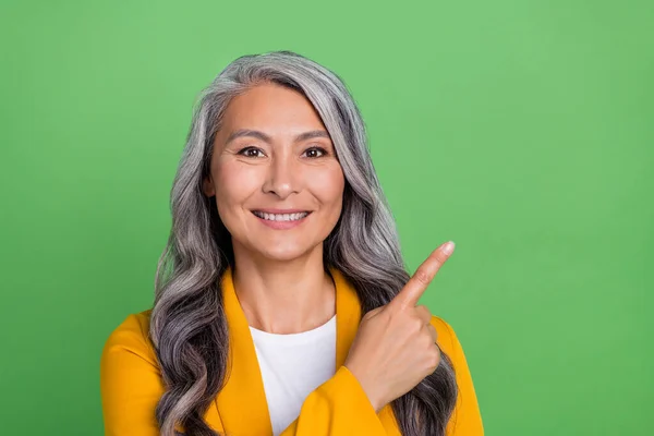 Фотографія старшої жінки вказує на порожній простір палець порадити маркетолога-агента ізольовано на фоні зеленого кольору — стокове фото