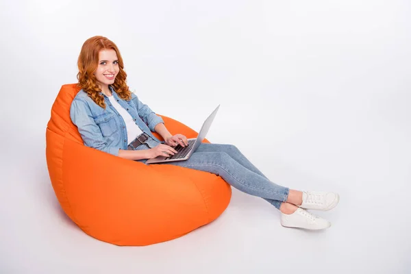 Foto panjang penuh wanita muda yang bahagia dan menarik, duduk manis, karung kacang, tersenyum, pegang laptop terisolasi di latar belakang warna abu-abu. — Stok Foto