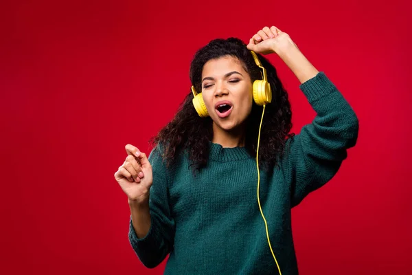 Foto van vrolijke mooie donkere huid jonge funky vrouw dans dragen hoofdtelefoon geïsoleerd op rode kleur achtergrond — Stockfoto