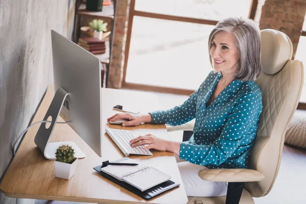 快乐的老年妇女的侧面照片快乐积极的微笑看浏览电脑坐在室内写字台办公室 — 图库照片