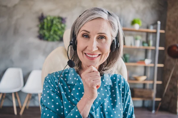 Фото веселой пожилой женщины счастливой позитивной улыбкой руки касаются подбородка носить наушники микрофон колл-центр эксперт в помещении — стоковое фото