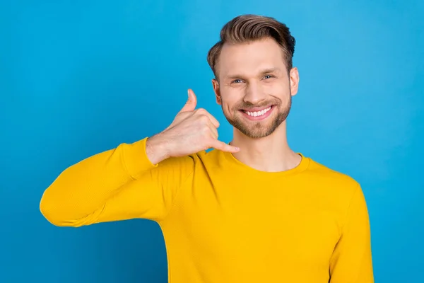 Photo de jeune gars heureux sourire positif montrer doigt indicatif téléphonique parler parler isolé sur fond de couleur bleue — Photo