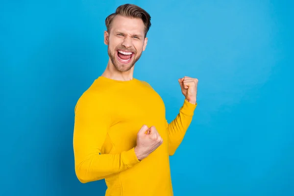 Profil boční fotografie mladého chlapa šťastný pozitivní úsměv oslavit vítězství vyhrát loterie pěsti ruce izolované přes modré barvy pozadí — Stock fotografie