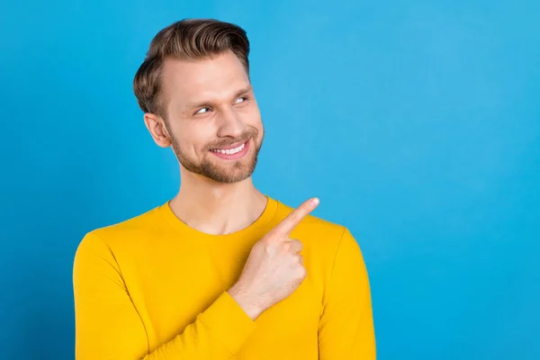 Foto av ung man glad positiv leende utseende indikerar finger tomt utrymme annons rekommenderar isolerad över blå färg bakgrund — Stockfoto