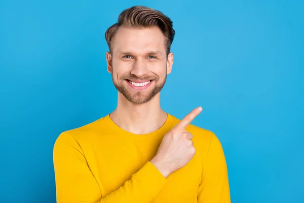 Foto av ung kille glad positiv leende peka finger tomt utrymme annons råd promo isolerad över blå färg bakgrund — Stockfoto