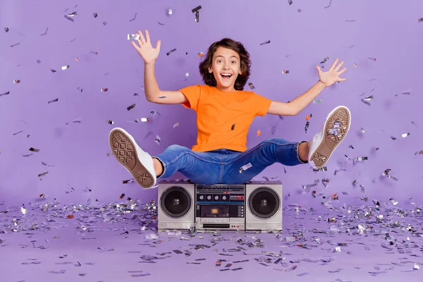 Volledige lengte body size foto vrolijke schooljongen zitten retro tape recorder partij vliegen confetti geïsoleerde violette kleur achtergrond — Stockfoto