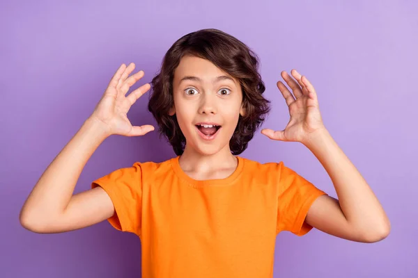 놀란 초등학생 이 주황색 티셔츠를 입을 벌리고 바라보고 있는 사진은 파스텔 보라색 배경을 띠고 있다. — 스톡 사진
