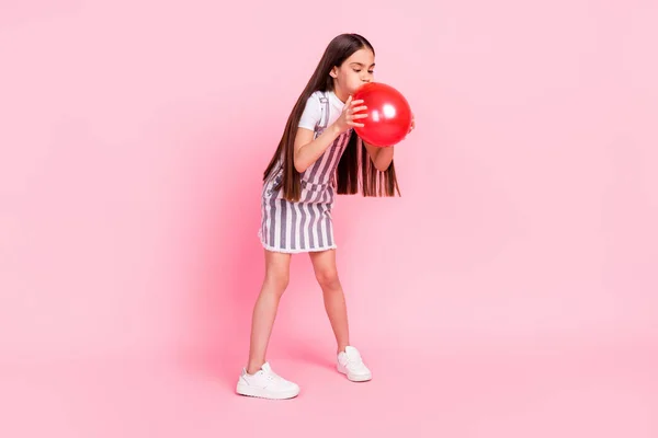 Πλήρες μήκος σώματος μέγεθος φωτογραφία μαθήτρια εισπνέει κόκκινο μπαλόνι αέρα ετοιμάζεται να κόμμα απομονωμένο παστέλ ροζ χρώμα φόντο — Φωτογραφία Αρχείου