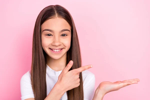 Foto av attraktiv ung positiv flicka peka finger hålla handen tomt utrymme objekt isolerad på rosa färg bakgrund — Stockfoto