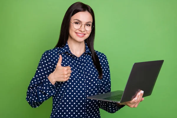 Фотографія оптимістичної брюнетки зачіска грн леді тримає ноутбук-шоу великий палець вгору одяг видовищ синя сорочка ізольована на зеленому кольоровому фоні — стокове фото