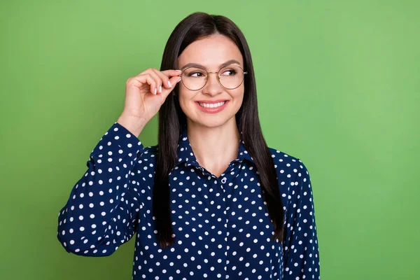 Foto van optimistische brunette kapsel slimme dame kijken lege ruimte dragen bril gestippelde shirt geïsoleerd op groene kleur achtergrond — Stockfoto