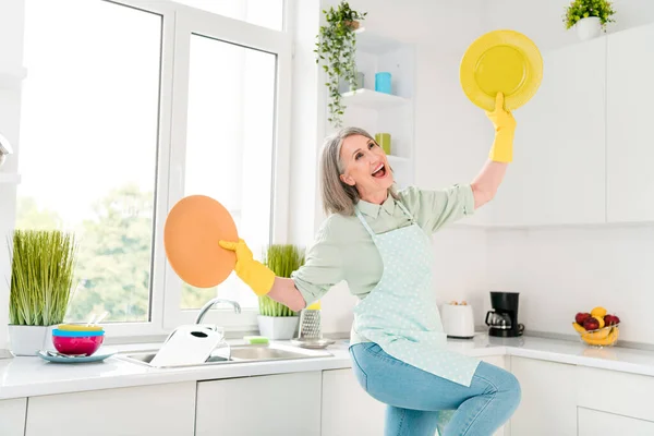Retrato de mulher de cabelos grisalhos alegre atraente fazendo pratos dançando se divertindo bom humor rápido serviço fácil em casa luz branca interior — Fotografia de Stock