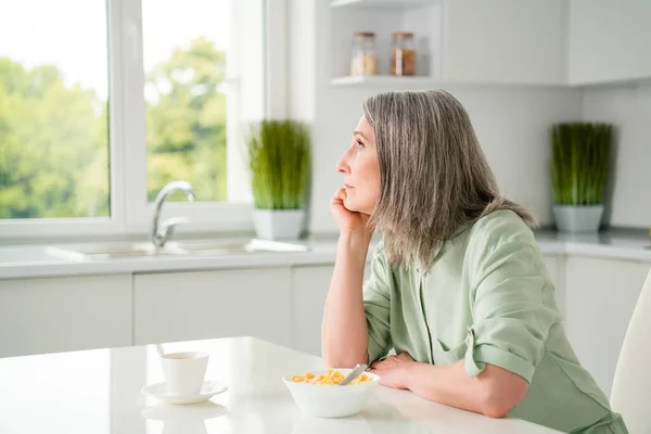 Profil boční pohled portrét atraktivní zasněné šedovlasé ženy snící jíst užitečné oběd doma světle bílé vnitřní — Stock fotografie