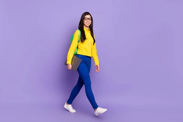 Foto de cuerpo completo de encantadora mujer joven agradable caminar mantenga portátil usar mochila aislada sobre fondo de color violeta — Foto de Stock