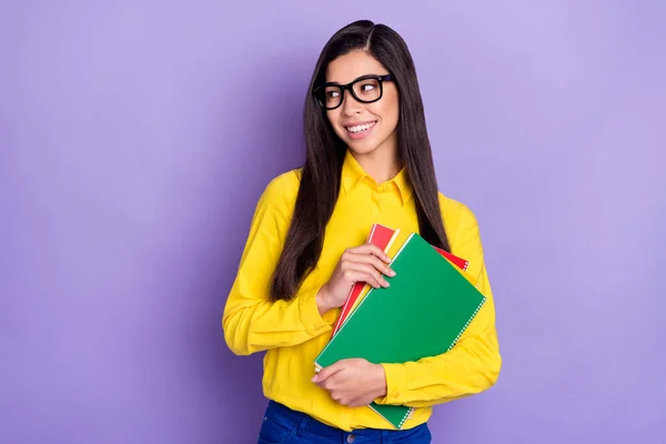 Foto de atraente jovem feliz senhora olhar espaço vazio mantenha as mãos cadernos isolados no fundo cor roxa — Fotografia de Stock