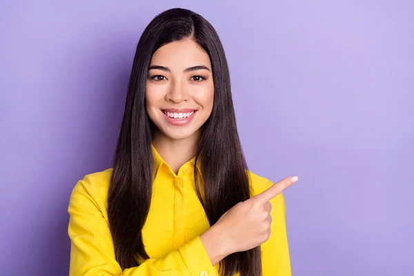 楽観的な茶色の髪の若い女性のポイントの写真空のスペースは紫の色の背景に隔離された黄色のシャツを着る — ストック写真