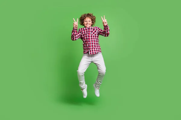 Volledige lengte lichaam grootte uitzicht van knappe vrolijke man springen plezier tonen v-teken geïsoleerd over glans groene kleur achtergrond — Stockfoto