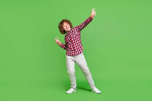 Plná délka velikosti těla pohled na atraktivní veselý chlap ukazující V-sign baví izolované přes jasně zelené barvy pozadí — Stock fotografie