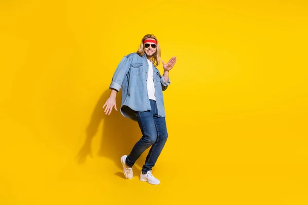 Foto de dulce divertido caballero joven usar jeans camisa gafas oscuras bailando sonriente aislado color amarillo fondo —  Fotos de Stock