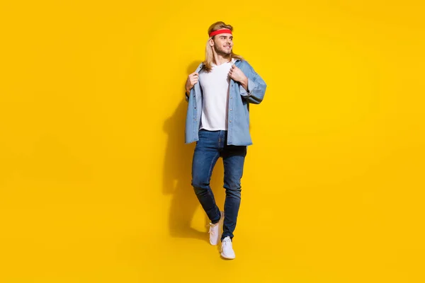 Foto van aantrekkelijke zoete jonge heer dragen jeans shirt lopen op zoek lege ruimte glimlachen geïsoleerde gele kleur achtergrond — Stockfoto